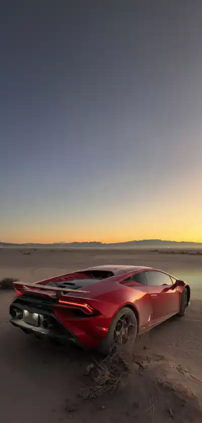 Background image of a Lamborghini Aventador in the desert at sunset