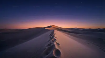 Desert of dunes under a starry sky at sunset