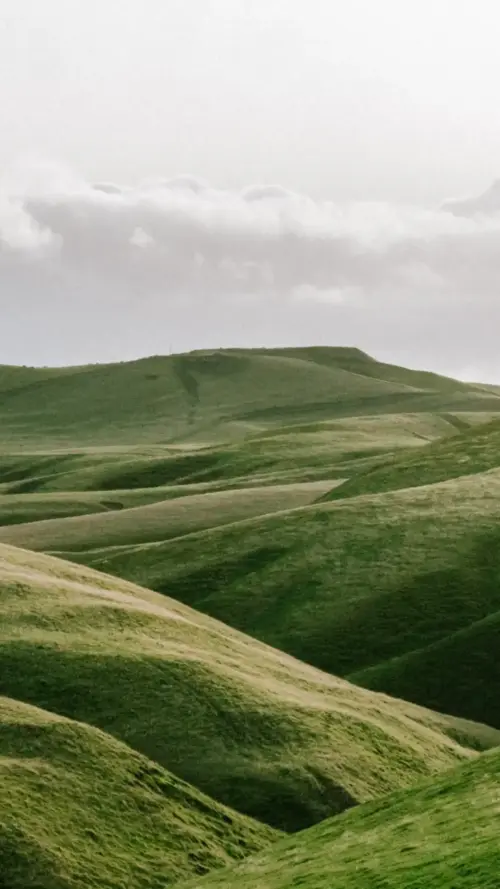 Green mountain and minimalist cloudy sky