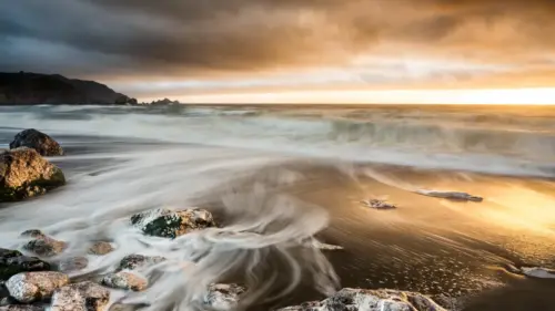 Waves on a rocky beach at sunset