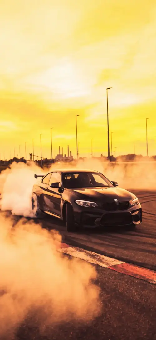 Black BMW M2 drifting under a yellow sky